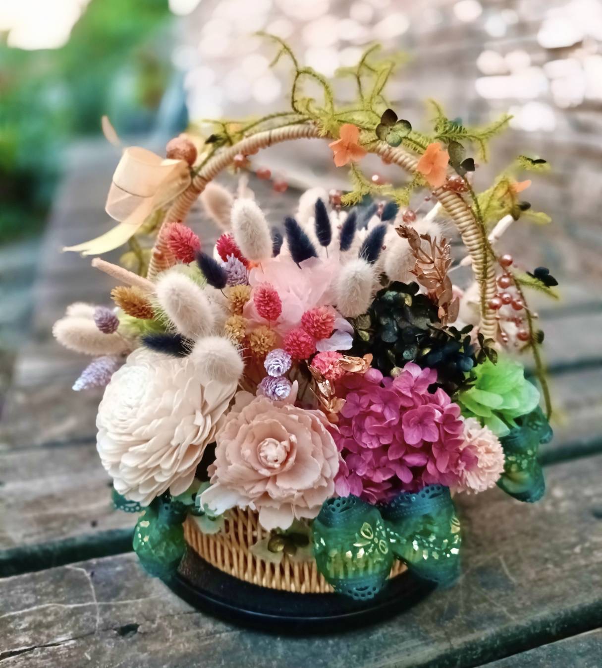 高坂嘉玲的永生花花籃：白粉色花朵、紫色花簇與綠色緞帶相互映襯。